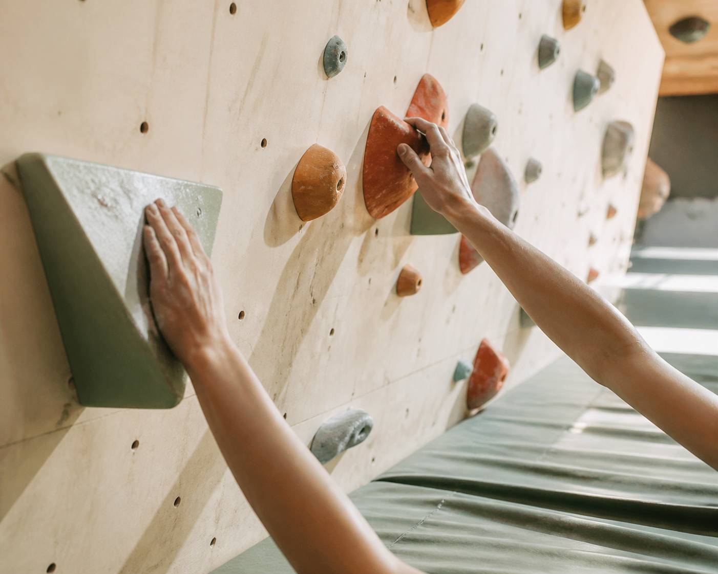 Mains à la craie saisissant des prises d'escalade colorées