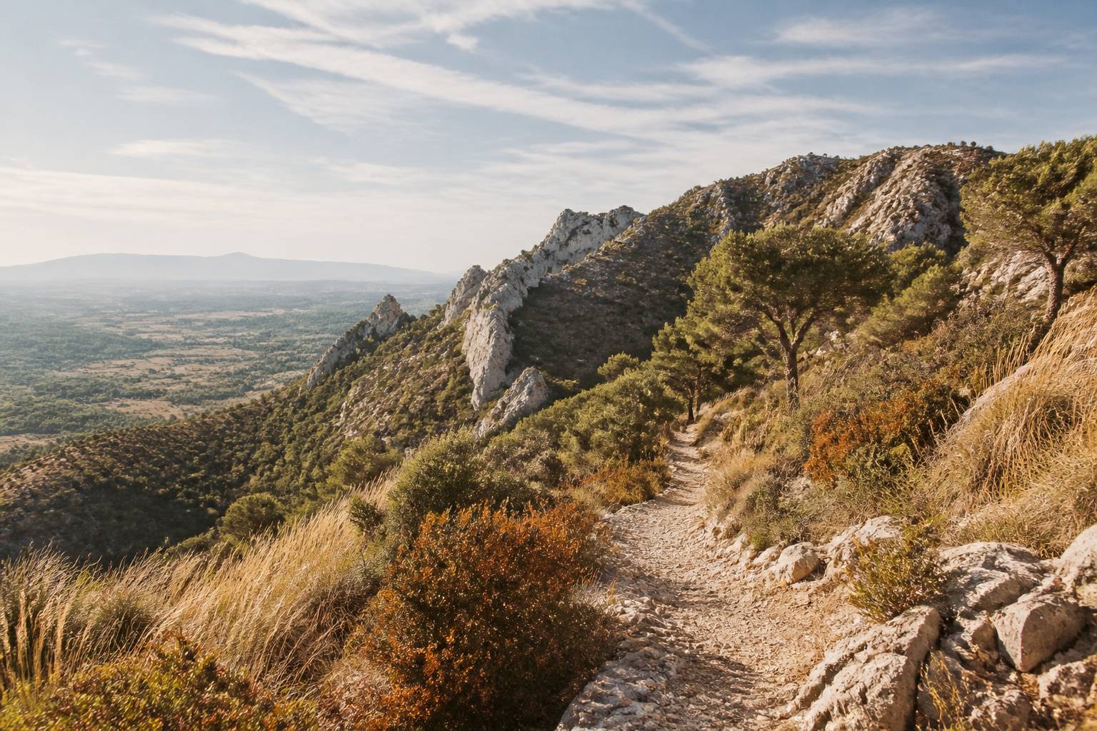 Crête calcaire du Luberon dominant une vallée avec un sentier pierreux